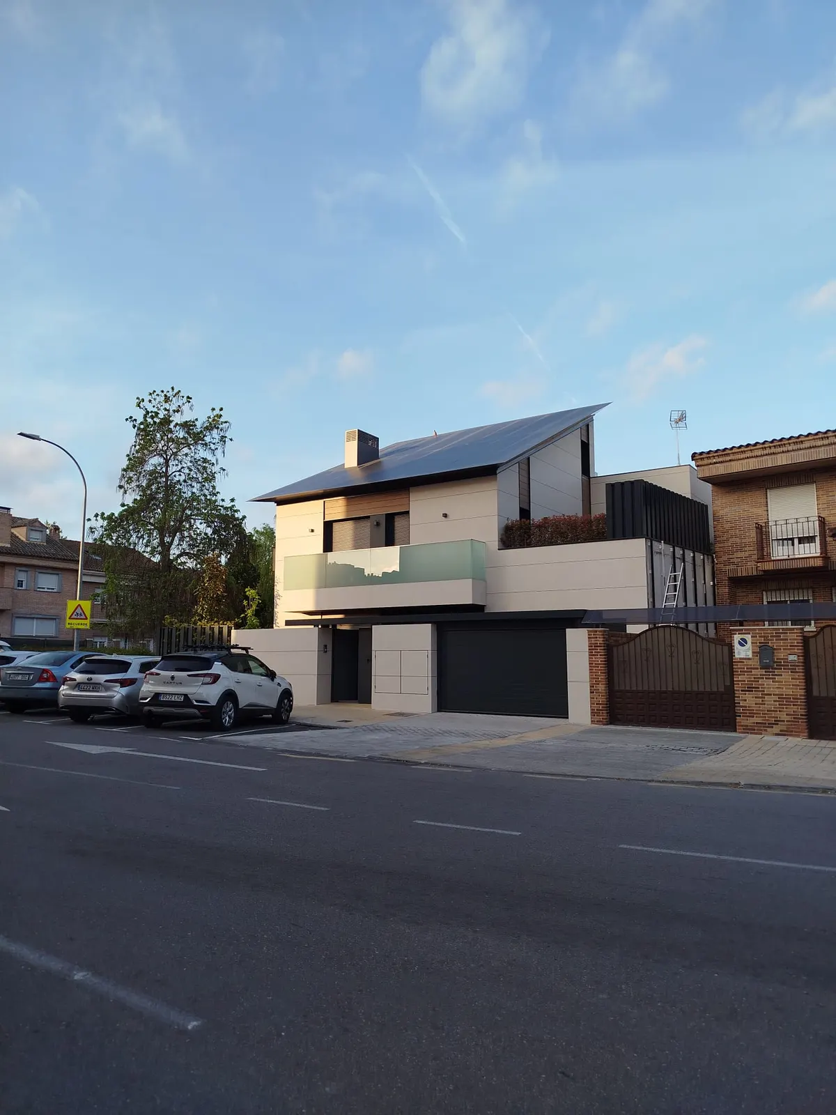 Fachada de chalet moderno en Pinto con ventanas de aluminio gris y barandilla de cristal