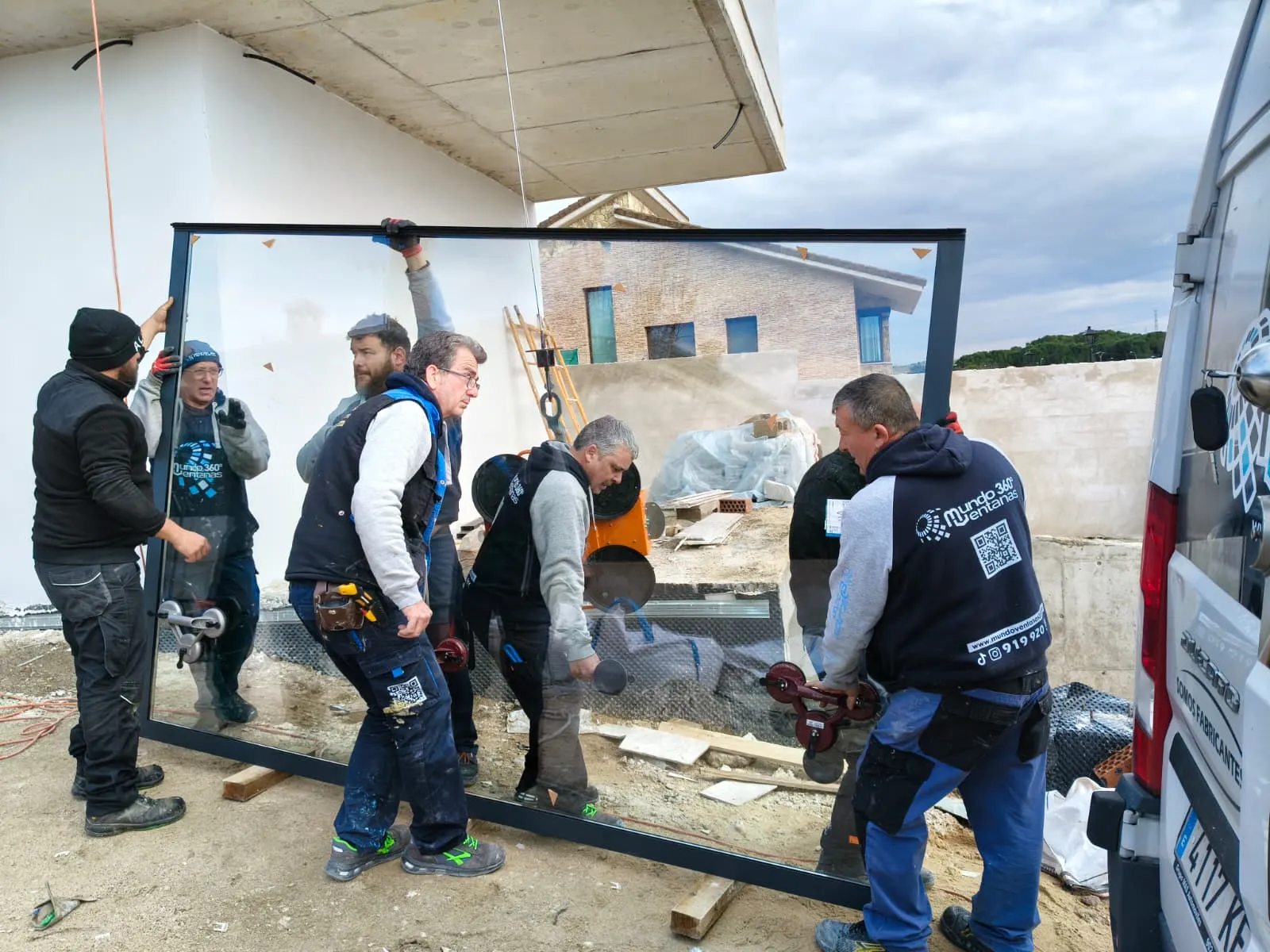 Equipo de Mundo Ventanas 360 trasladando un cristal de gran formato en una obra en Villamanta
